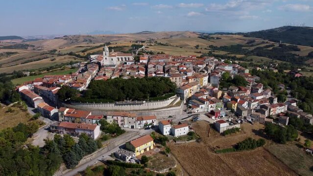 Aerial drone view with slow turn of Monteleone di Puglia, old small town in Apulia, southern Italy, the highest village in the whole region, with picturesque houses, narrow cobbled streets and a park