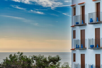 Blick auf das Meer mit weißer Hausfassade und blauer Keramik auf den Balkonen in Südeuropa.