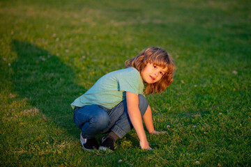 Happy smiling child boy relaxing on the grass. Cute kid boy enjoying on grass field and dreaming. Kids on green grass background.