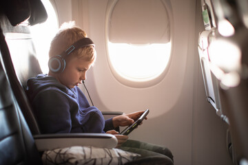 Little boy traveling on airplane using a tablet 