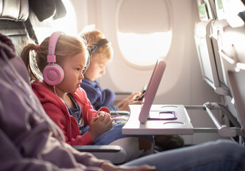 Adorable little boy girl travel by plane. Cute Kids sit at the window of an airplane watching...