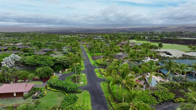 Aerial Kona Hawaii tropical luxury homes golf course. Big Island. Luxury homes on coast with golf course. Volcanic lava flow. Economy is tourism based. Water tropical beach recreation.