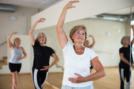Group of three mature women performing ballet dance in exercise room. © JackF