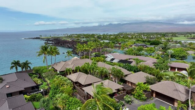 Aerial Kona Hawaii tropical luxury homes ocean coast. Big Island. Luxury homes on coast with golf course. Volcanic lava flow. Economy is tourism based. Water tropical beach recreation.