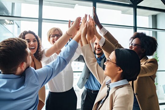 Diverse group of business professionals show unity and agreement by raising hands in office.
