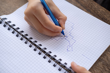 10-year-old boy drawing graphic dictation in checkered notebook, moving one line to left and two...