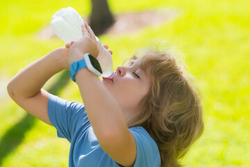 Child drinking water. Kid enjoy pure fresh mineral water. Outdoor kid boy drinking pure bottle from glass. Close up portrait of kid drinking water in park. Healthy water to refreshment. - obrazy, fototapety, plakaty