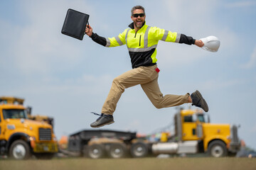 Construction man excited jump with helmet. Builder in helmet outdoor portrait. Worker in hardhat. Construction engineer worker in builder uniform on construction. Excited foreman jump.