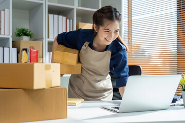 Young woman online business owner is using laptop to prepare the package for delivery to the customer