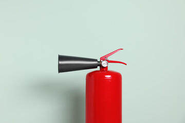 Red fire extinguisher against light green background