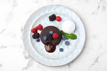 Delicious chocolate fondant served with fresh berries and ice cream on white marble table, top view