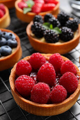 Tartlet with fresh raspberries on cooling rack, closeup. Delicious dessert