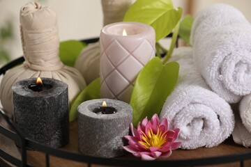 Composition with different spa products and burning candles on tray, closeup