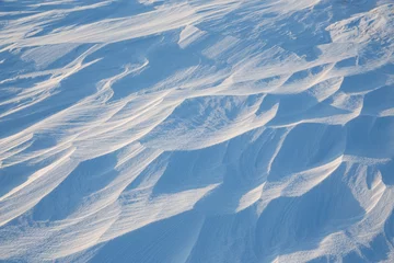 Fotobehang Snow texture. Wind sculpted patterns on snow surface. Wind in the tundra and in the mountains on the surface of the snow sculpts patterns and ridges (sastrugi). Arctic, Polar region. Winter background © Andrei Stepanov