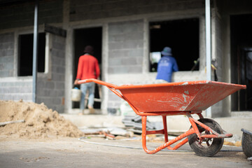 Orange wheelbarrow cart at the construction site.