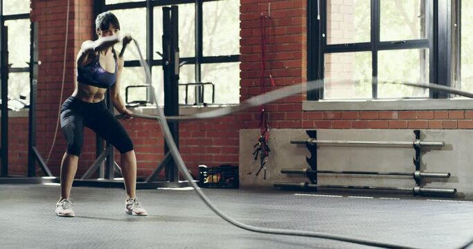 Woman, battle rope and exercise in gym with muscle training, health and workout for bodybuilding. Wellness, strong athlete and sports with endurance, resilience and challenge, power and performance