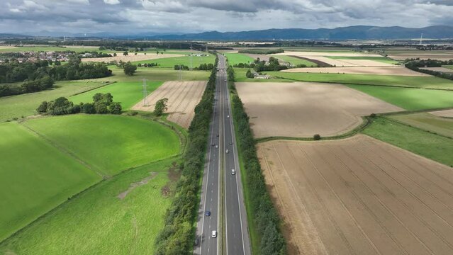 4K Aerial over the M9, Edinburgh, the Capital of Scotland, United Kingdom. Freeway with cars centre frame with farmland and and power cables left and right of frame