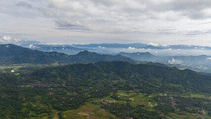 Fototapeta premium Aerial drone of farmland with plantings and mountains. Farmland in the tropics. Bukittinggi, Sumatra. Indonesia.