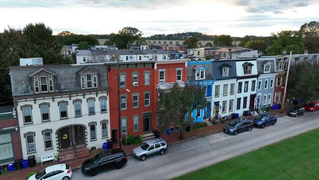 Colorful row homes in urban neighborhood in USA. Aerial rising shot of houses revealing river and bridges in America during sunset.