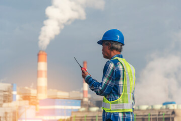 Backside Electrician engineer man hand holding blue hardhat at Power stations manufacturing electrical plant. Technician worker blue hardhat helmet Engineer with steam smokestack industry background