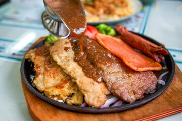 A delicious and tempting sizzling steak, chicken, and pork chop in a Hong Kong-style tea restaurant