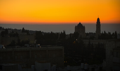 Dramatic sunrise in Israel. Synagogue view from above against orange sky and mountains line background. Sunrise view in Jerusalem, concept image for this war times.