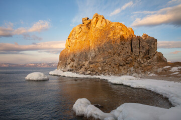 Baikal Lake on cold December morning. View of natural landmark of Olkhon Island - the Shamanka Rock and freezing bay in sunrise light. Natural background. Scenic landscape. Travel and outdoors