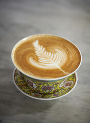 hot coffee cappuccino latte art in a antique chinese cup with grey background.