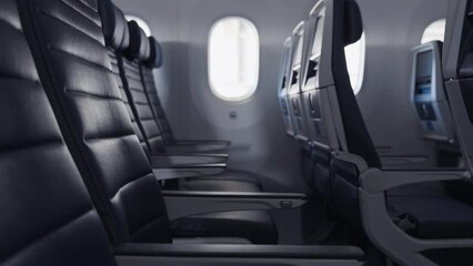 Slow push in across a row of blue, empty leather seats in a commercial passenger airplane.