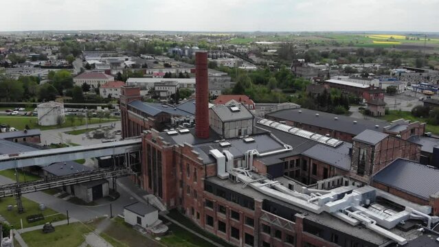 Aerial orbit shot of the Arche Hotel Żnin inside old sugar factory in Poland. The tall chimney of the factory is a famous landmark, rising above the surrounding landscape