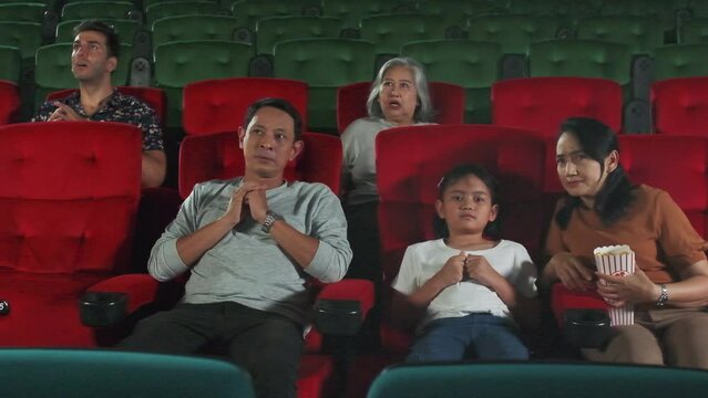 Various people in theater. Asian family and multiracial audiences are scared of watching thriller and horror cinema, frightened together on movie stage, and entertainment lifestyle with film art show.