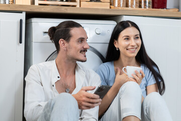 Man and woman couple sitting in kitchen drinking coffee at home