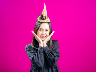 Portrait of an Asian Indonesian woman wearing a Halloween-themed costume with a witch hat, posing...