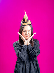 Portrait of an Asian Indonesian woman wearing a Halloween-themed costume with a witch hat, posing...