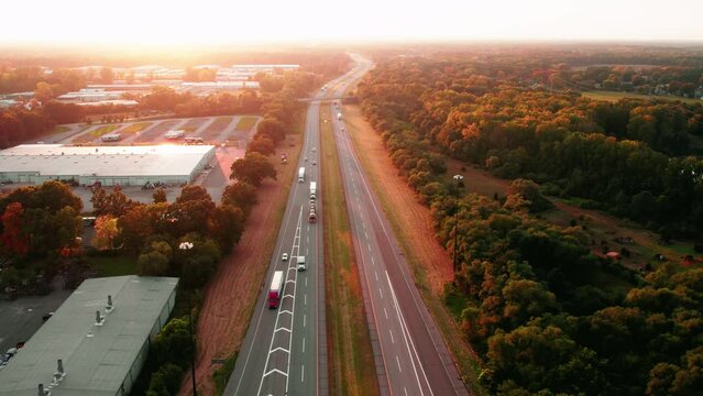 Magic sunset aerial views of trucking freight transported by semi truck and trailers on Interstate I-80 Elkhart Indiana. Dryvan, reefer, car hauler carriage, flatbeds on highway.Warehouse on left