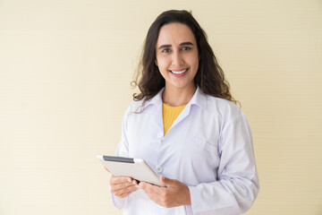 Fototapeta premium Portrait of smiling young female doctor or young nurse wearing white uniform and working digital tablet at hospital