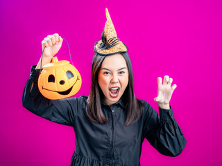 Portrait of an Asian Indonesian woman wearing a Halloween-themed costume with a witch hat,...
