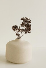 Modern beige ceramic vase with dry  grass on white table near white wall. Scandinavian interior accessories. Poster