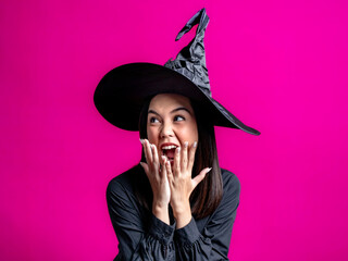 Portrait of an Asian Indonesian woman wearing a Halloween-themed costume with a witch hat, looking surprised and screaming. Isolated against a magenta background.