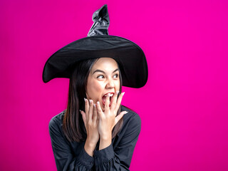 Portrait of an Asian Indonesian woman wearing a Halloween-themed costume with a witch hat, looking...
