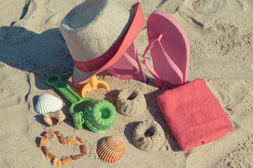 Accessories and children toys for playing or relax on sand at beach. Straw hat, flip flop and...