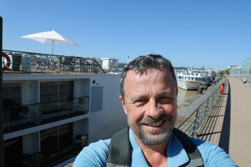 selfie portrait of happy handsome white man with river cruise boat background in bordeaux quay