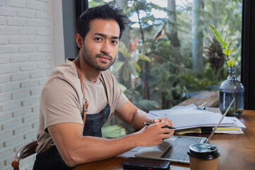 Handsome Indian male restaurant owner sit and looking at camera with confidence. Man employee...