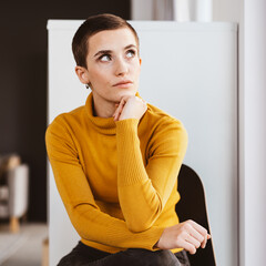 Young Modern Woman in Yellow Sweater Sitting in Office, Deep in Thought