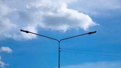 Electrical pole or electric pole with a background of blue sky and white clouds.
