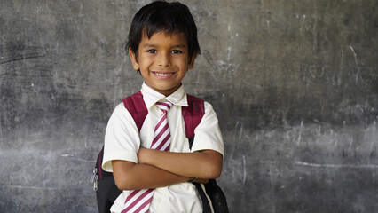 Portrait of happy indian teenager school boy with backpack holding books. Smiling young asian male kid looking at camera.