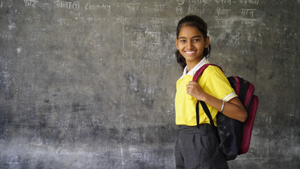 Portrait of happy indian teenager school girl with backpack holding books. Smiling young asian female kid looking at camera. - obrazy, fototapety, plakaty