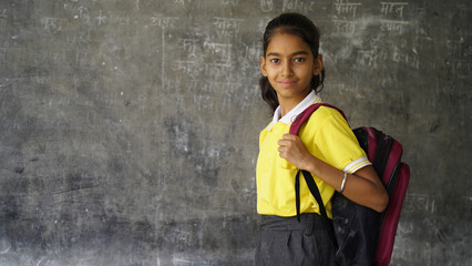 Portrait of happy indian teenager school girl with backpack holding books. Smiling young asian female kid looking at camera.