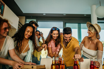 A joyful mix of friends, enters a lively daytime celebration, adding to the excitement with their arms full of mouthwatering treats and beverages