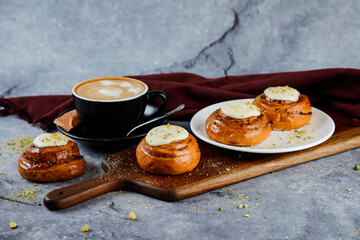 Cinnamon Roll served on wooden board with cup of coffee latte art isolated on napkin side view of french breakfast baked food item